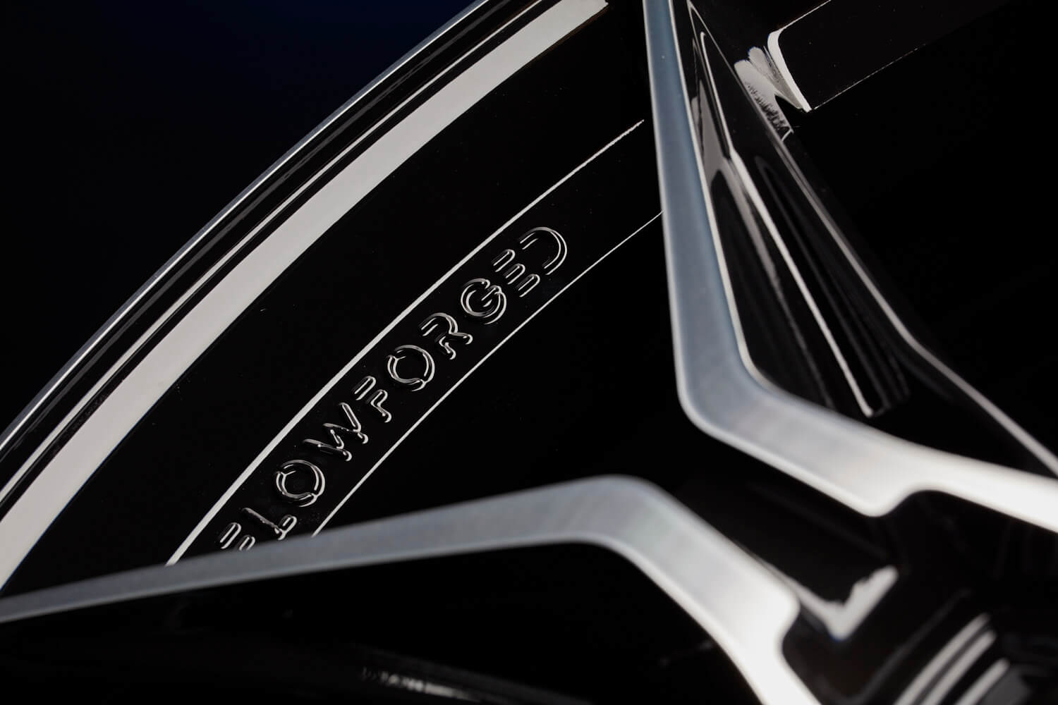 Nahaufnahme einer schwarz-silbernen Autofelge mit der Gravur FLOWFORGED