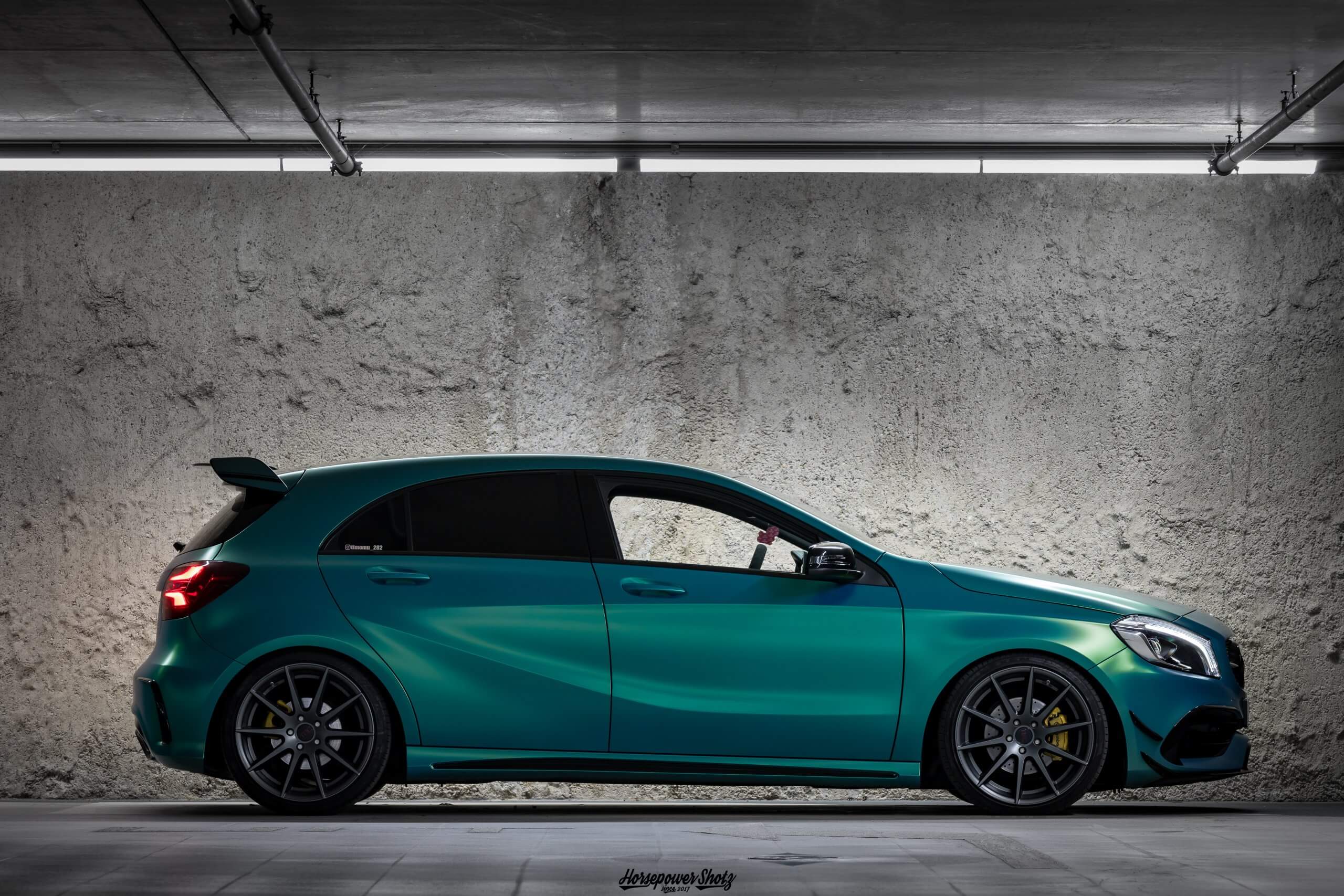 Ein türkisfarbener Hatchback steht in einer Tiefgarage vor einer Betonwand