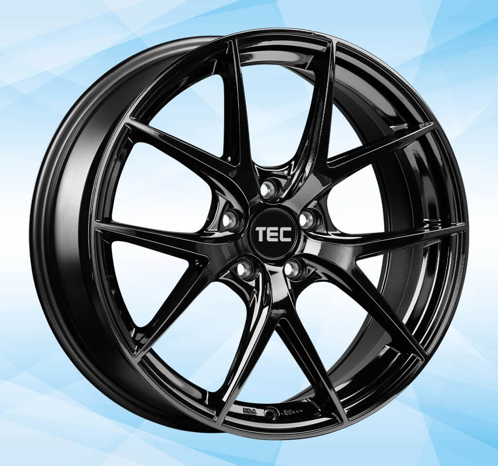 Glänzende schwarze Alufelge mit TEC-Logo in der Mitte, präsentiert vor blauem, geometrischen Hintergrund