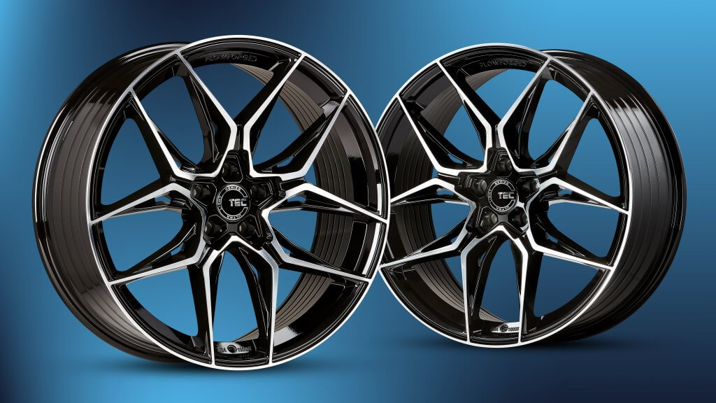 Zwei schwarz-silberne Alufelgen mit Mehrspeichen-Design vor einem blauen Farbverlauf-Hintergrund