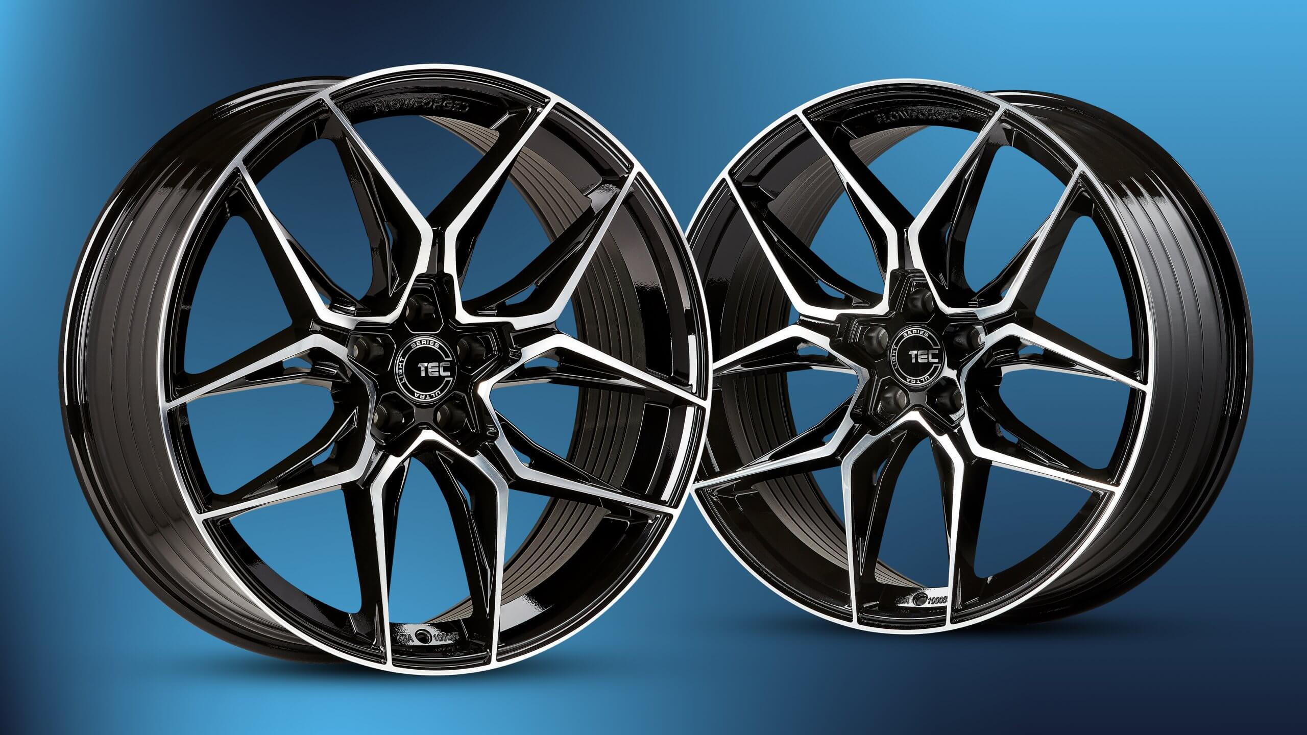 Zwei schwarz-silberne Alufelgen mit Mehrspeichen-Design vor einem blauen Farbverlauf-Hintergrund